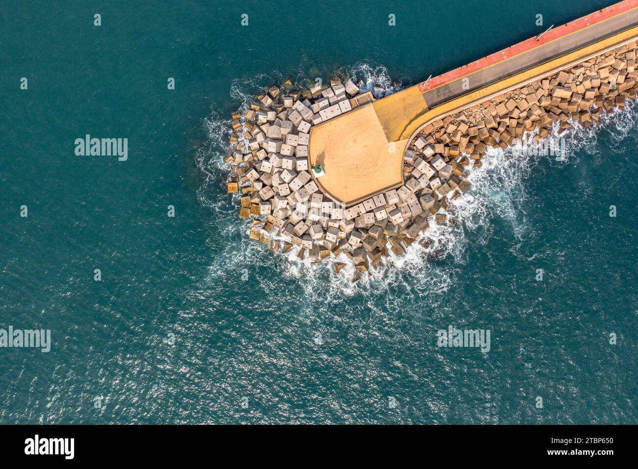 Pier in harbor in Mediteranean sea with concrete stone breakwater. Stock Photo