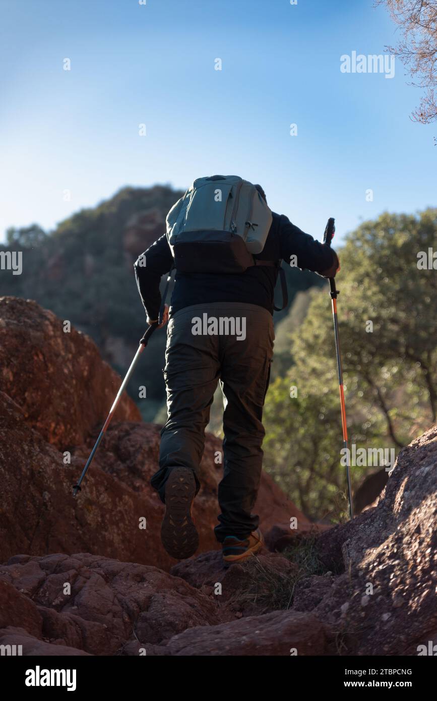 Middle-aged man climbs the mountain in the Garraf Natural Park, supported by hiking poles. Stock Photo