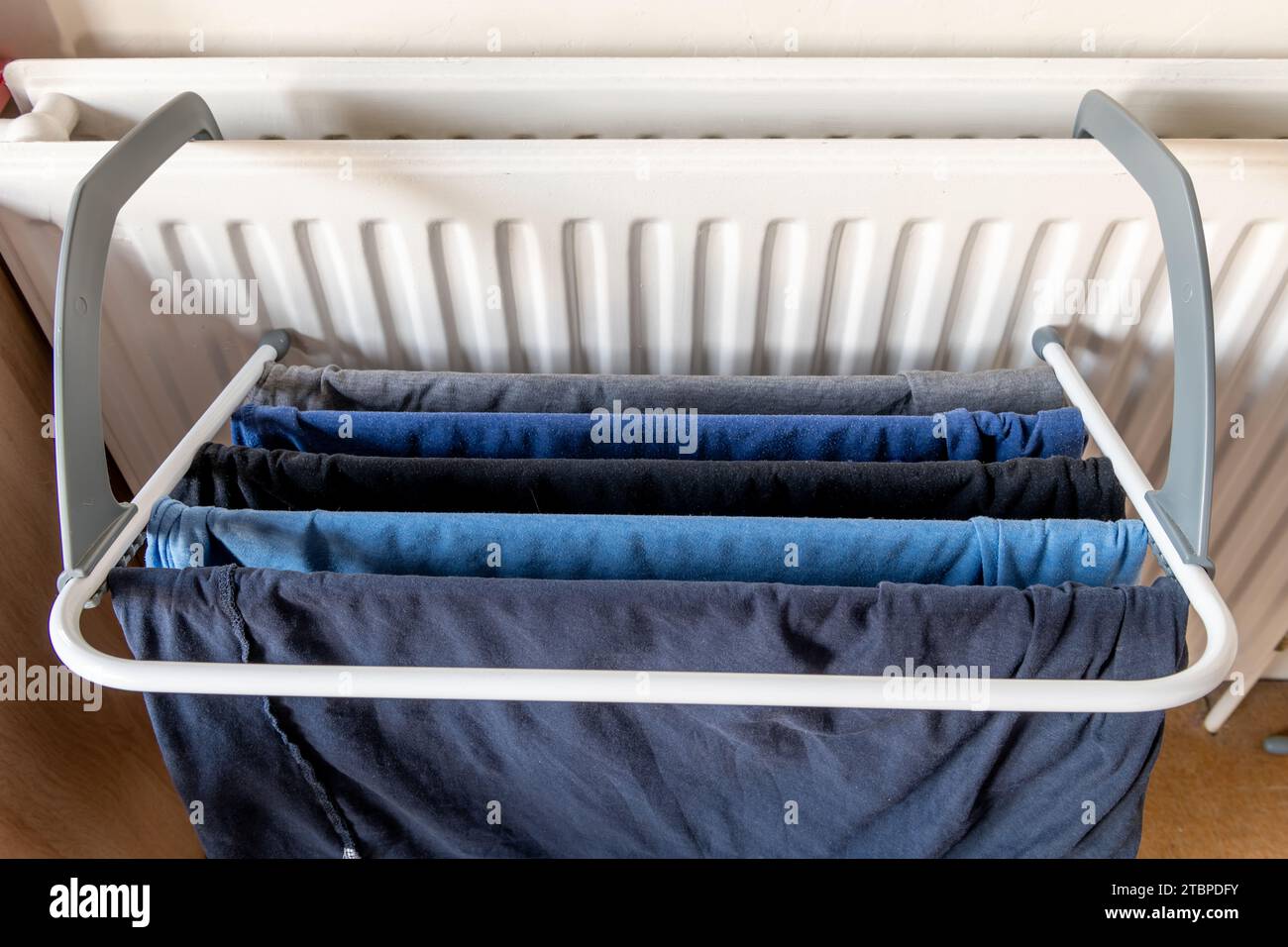 Laundry clothes drying on a rack attached to a home heating radiator. Stock Photo