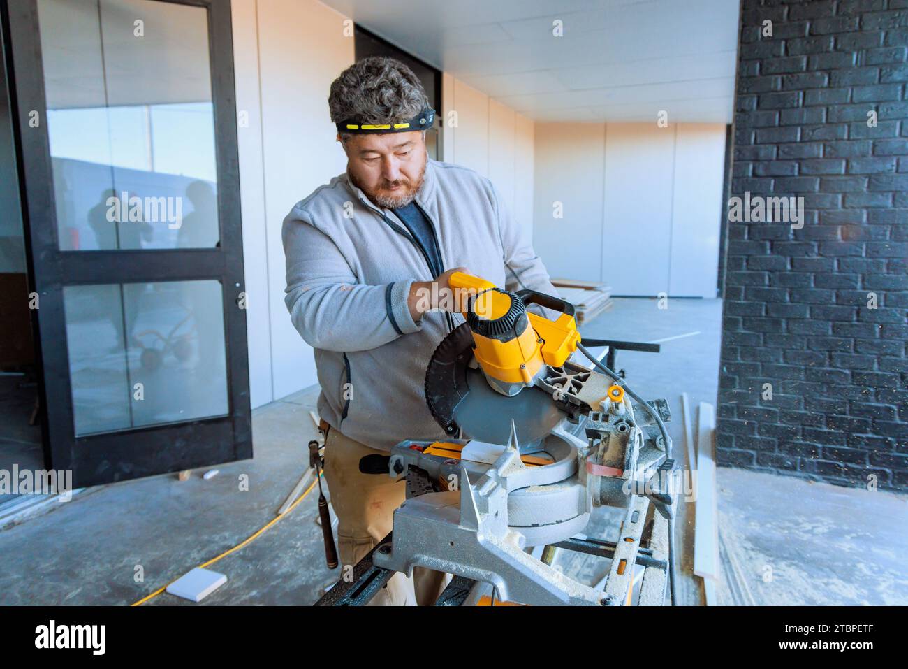 Trim worker cutting base wooden moldings with chop saw Stock Photo Alamy