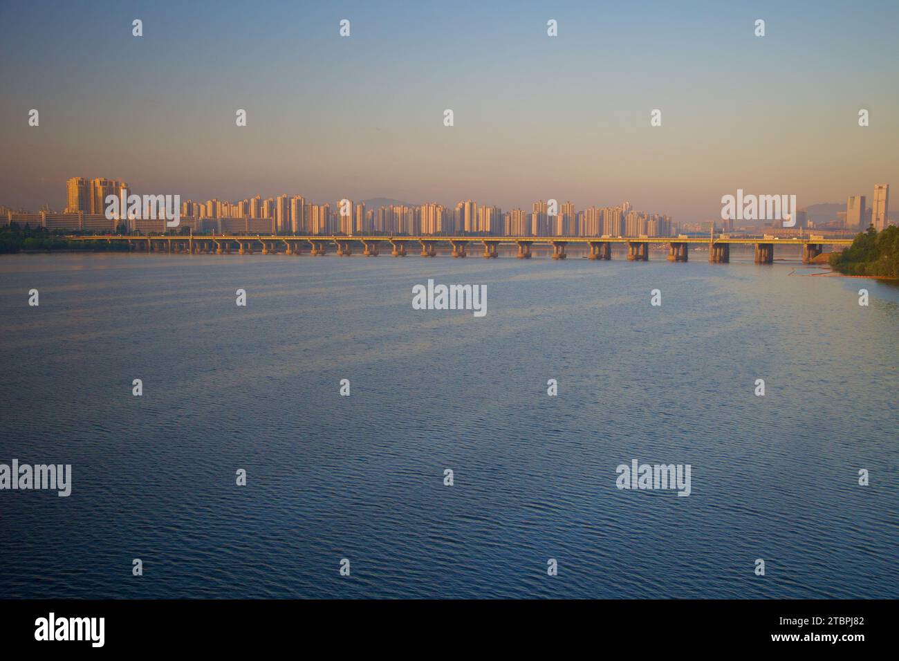 The Han River in Seoul welcomes the day with a tranquil dawn, mirroring the soft hues of the morning sky. This serene scene captures the quietude of t Stock Photo