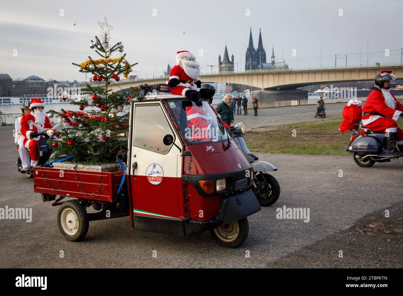 Piaggio Ape with Christmas tree, members of the Vespa scooter club RheinSchalter Koeln dressed as Santas gather on Deutzer Werft before a ride through Stock Photo