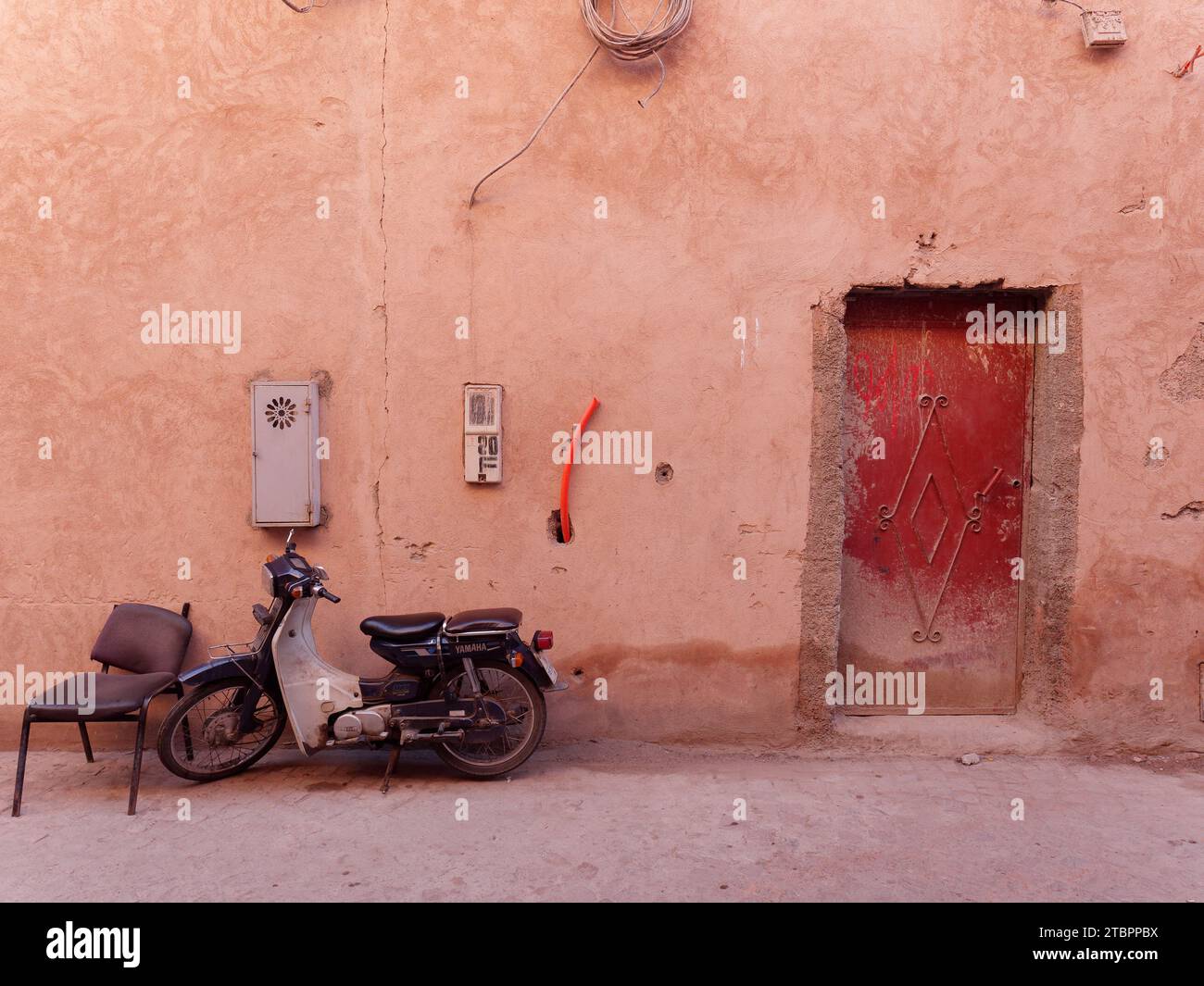 Vintage motorbike beside a brown door and wall in the Medina (Historic Walled Centre) Marrakesh aka Marrakech, Morocco, December 08, 2023 Stock Photo
