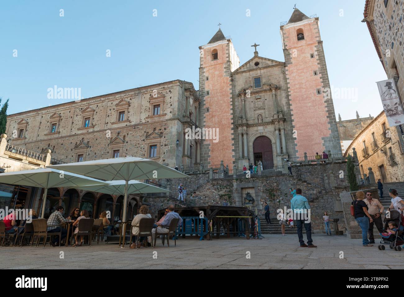 The church of San Fransisco seen from the square of St. George with tourists sitting under parasols. Caceres, Extremadura, Spain. Stock Photo