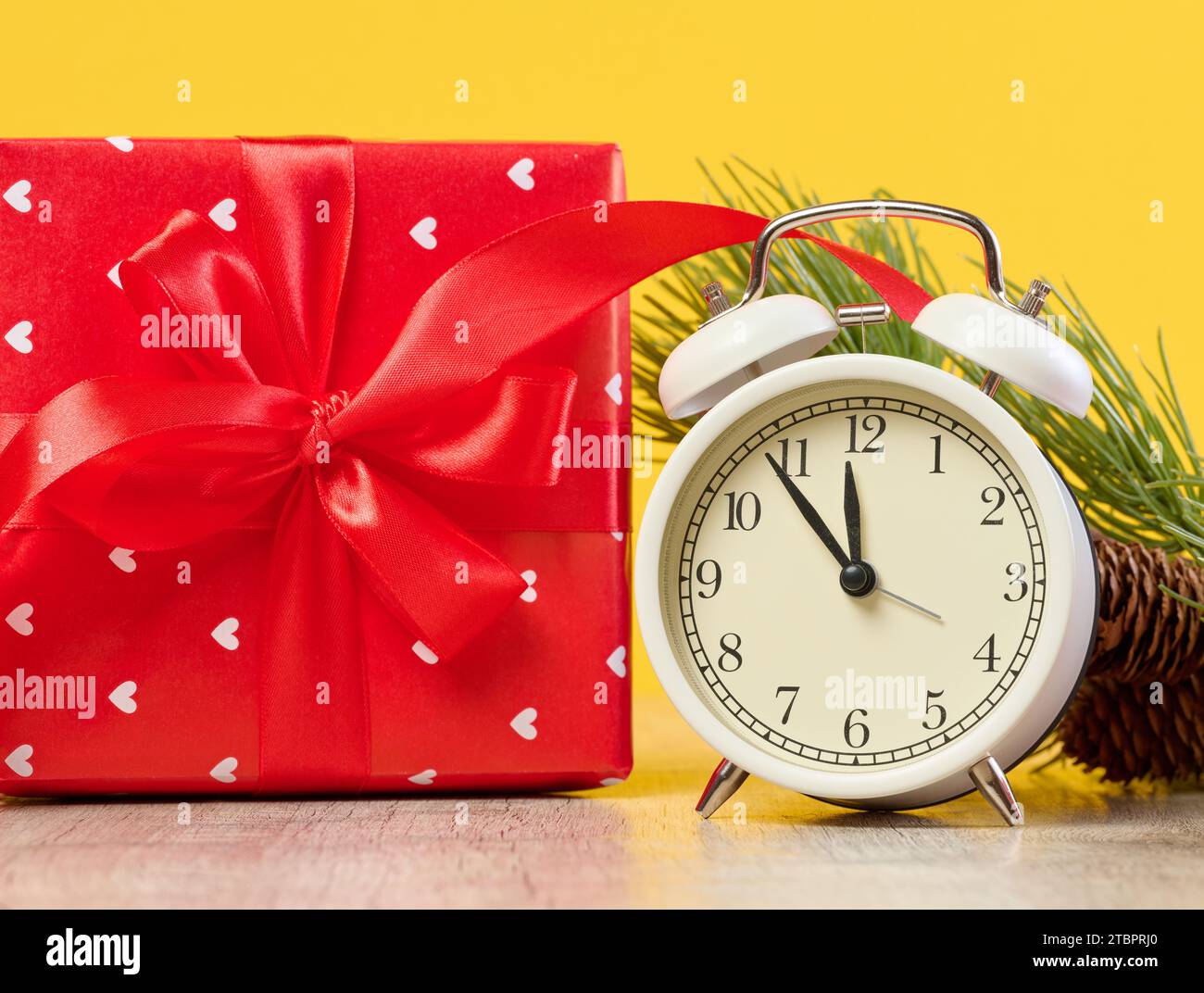 Alarm clock and stack of red gift boxes on yellow background Stock Photo