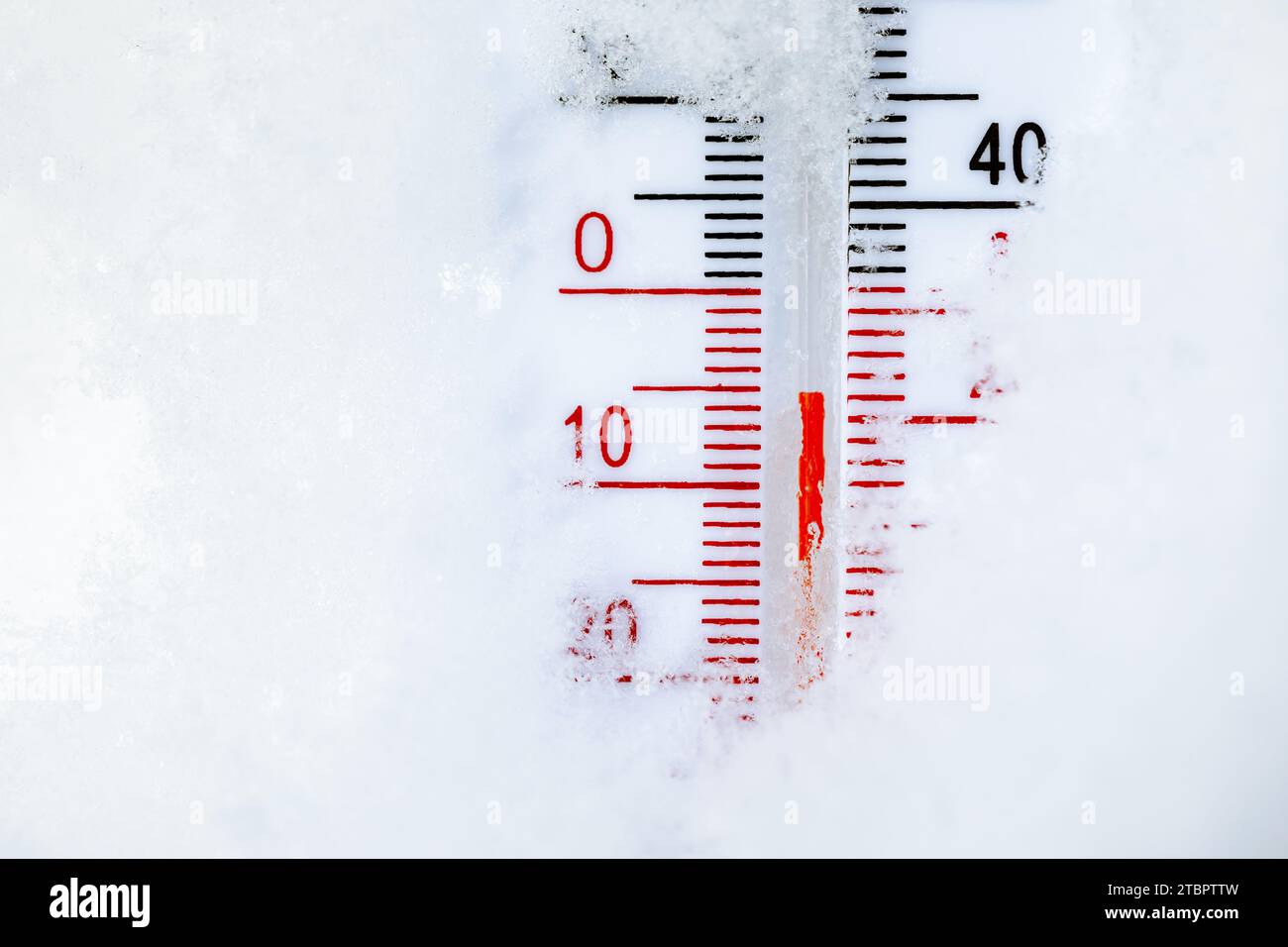 Thermometer with both Celsius and Fahrenheit scales placed in fresh snow indicating cold winter temperature Stock Photo