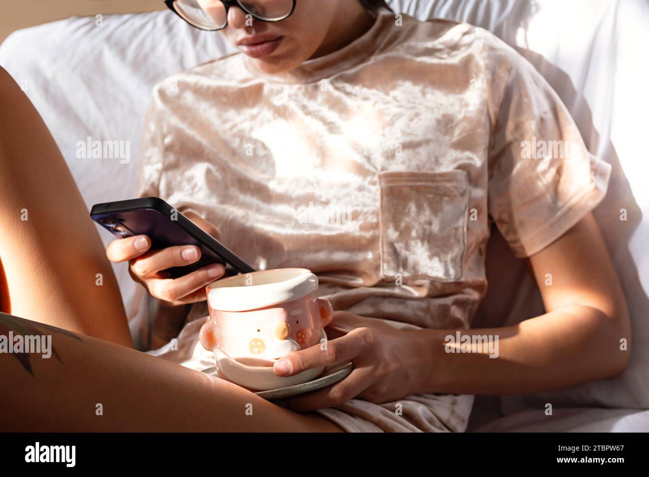 Woman drinking tea and texting on smartphone. Cozy winter weekend morning. Stock Photo