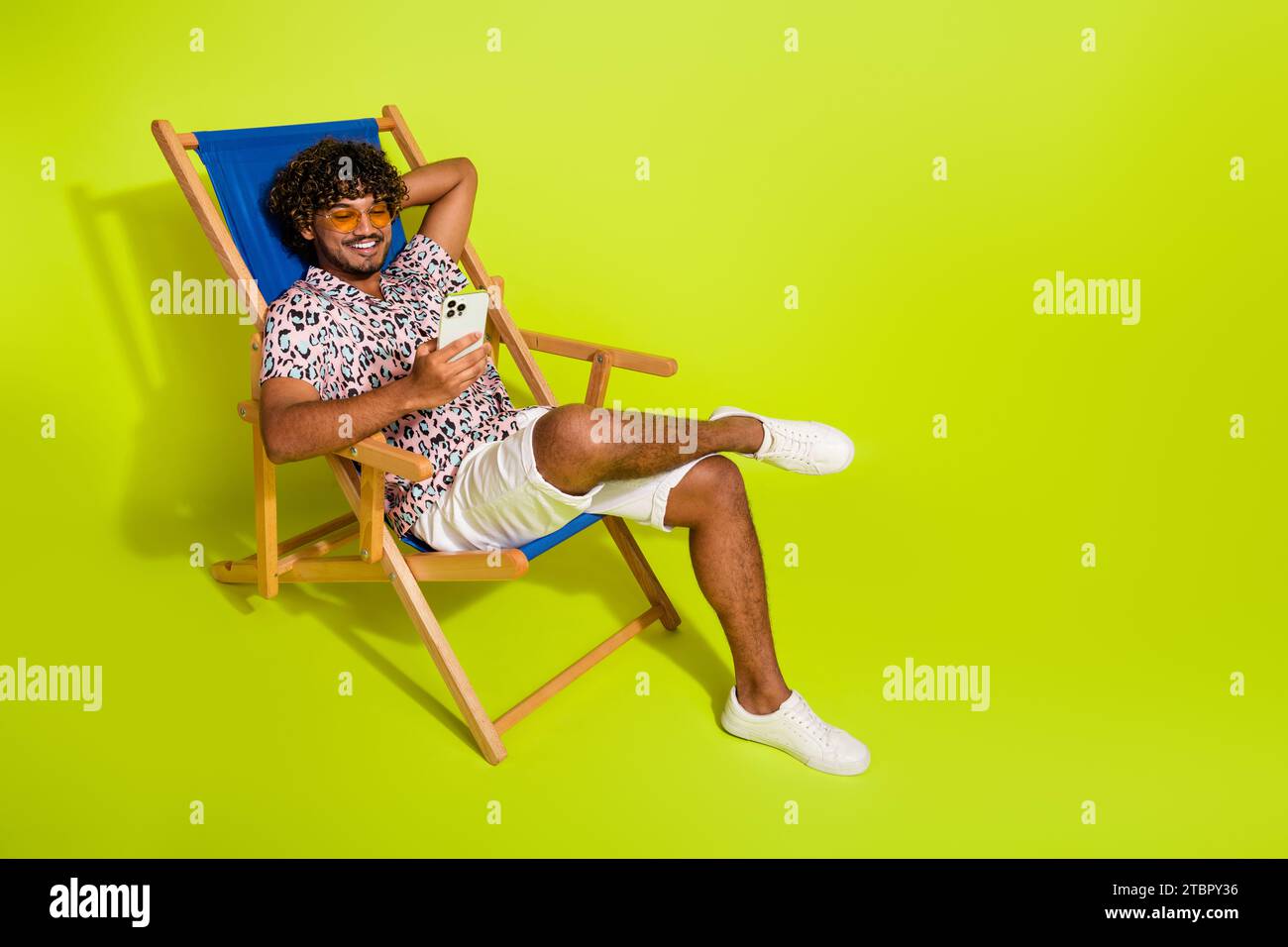 Full body photo of handsome young man sit sunbed hold device wear