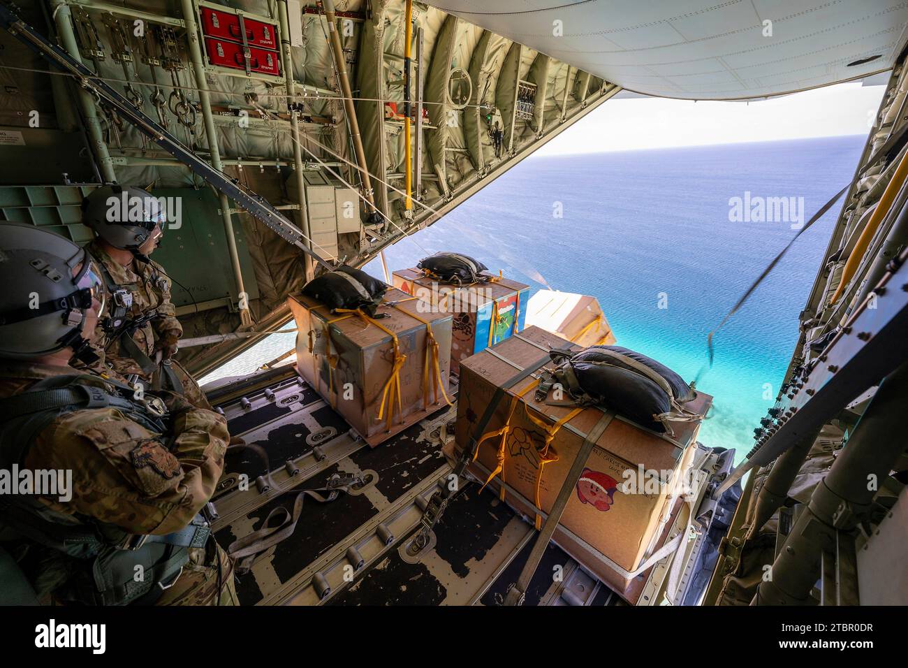 Satawan Atoll, Federated States of Micronesia. 05 December, 2023. U.S. Air Force Senior Airman Joseph Snell, left, and Staff Sgt. Matthew Muravez, 36th Expeditionary Airlift Squadron loadmasters push humanitarian bundles out of a U.S. Air Force C-130J Super Hercules aircraft during Operation Christmas Drop, December 5, 2023 in Satawan Atoll, Micronesia. Operation Christmas Drop is the oldest humanitarian and disaster relief mission delivering 71,000 pounds of food, gifts, and supplies to assist remote island communities in the South Pacific. Credit: Yasuo Osakabe/US Airforce Photo/Alamy Live Stock Photo