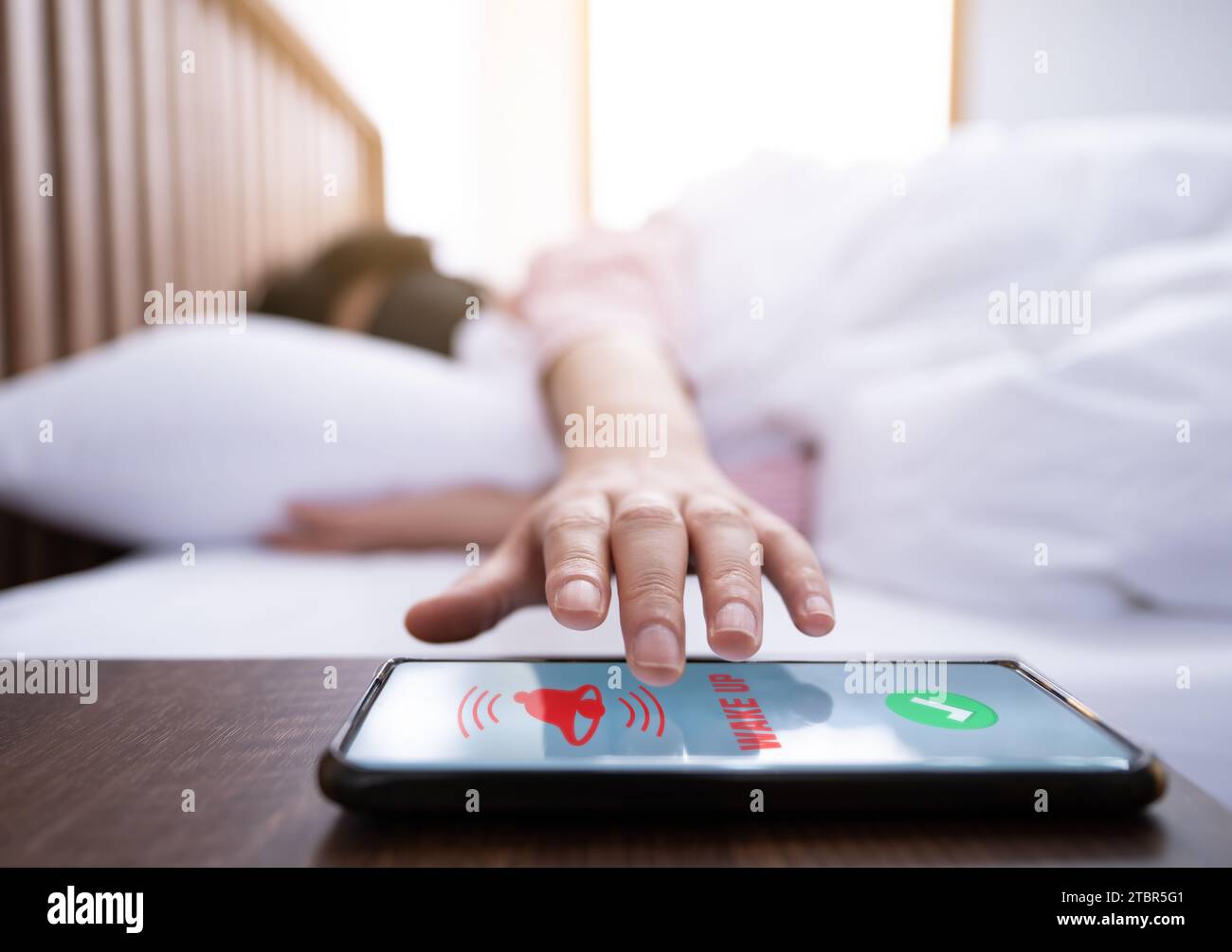 A woman wearing an eyepatch tries to touch her smartphone while waking up from sleep Stock Photo