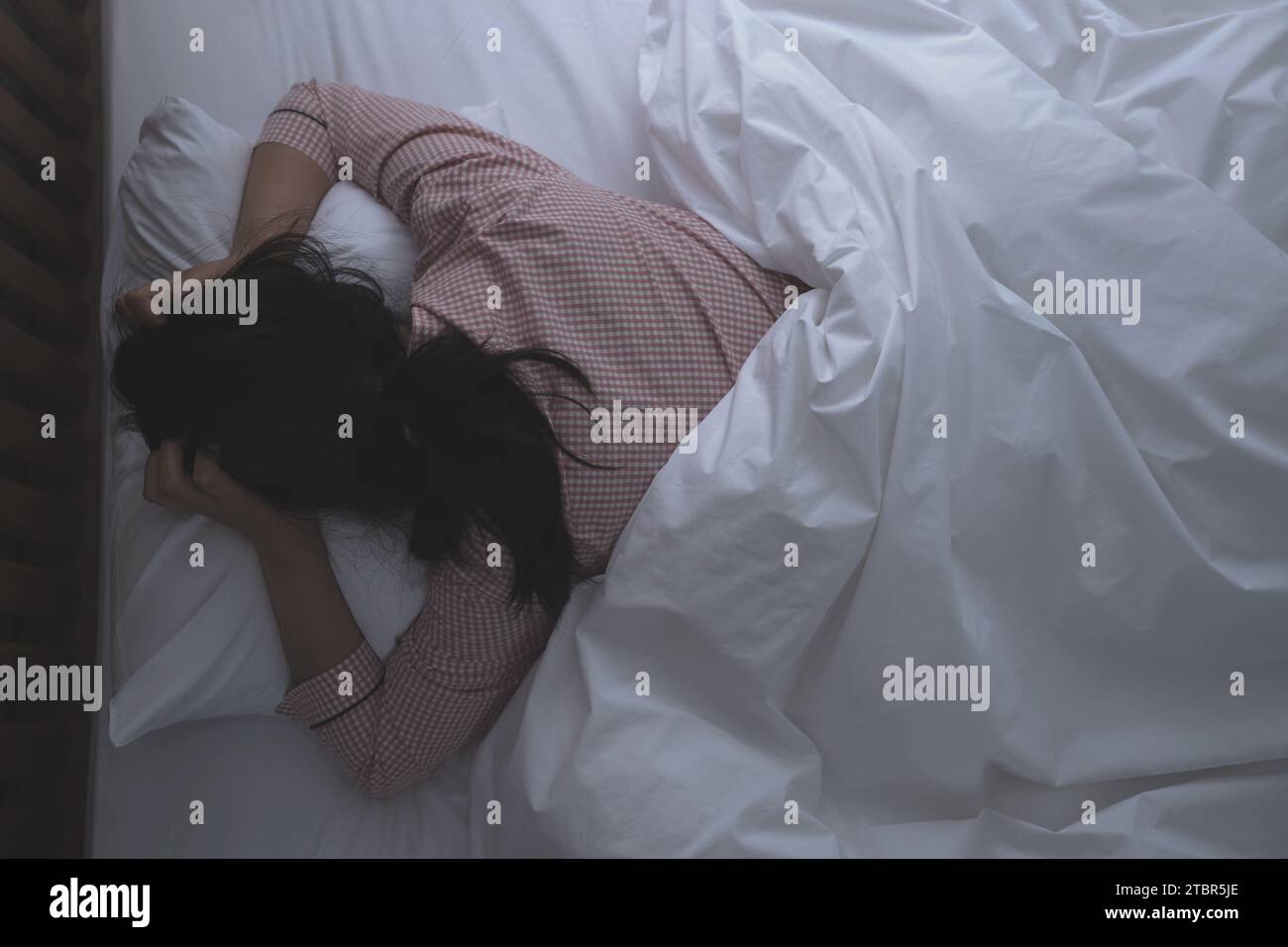 A woman suffering from insomnia due to noise between floors at night Stock Photo