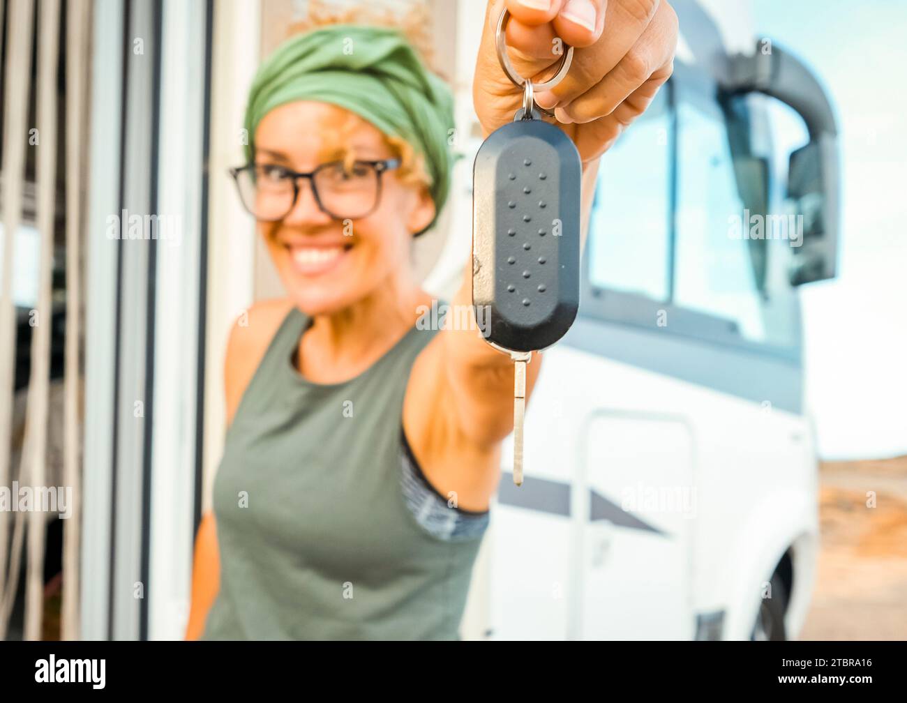 Happy new buyer owner of camper van motorhome show at the camera her keys with happiness. New house and vehicle for vacation concept scene. Travel vanlife lifestyle. Adventure. Nomadic people female Stock Photo