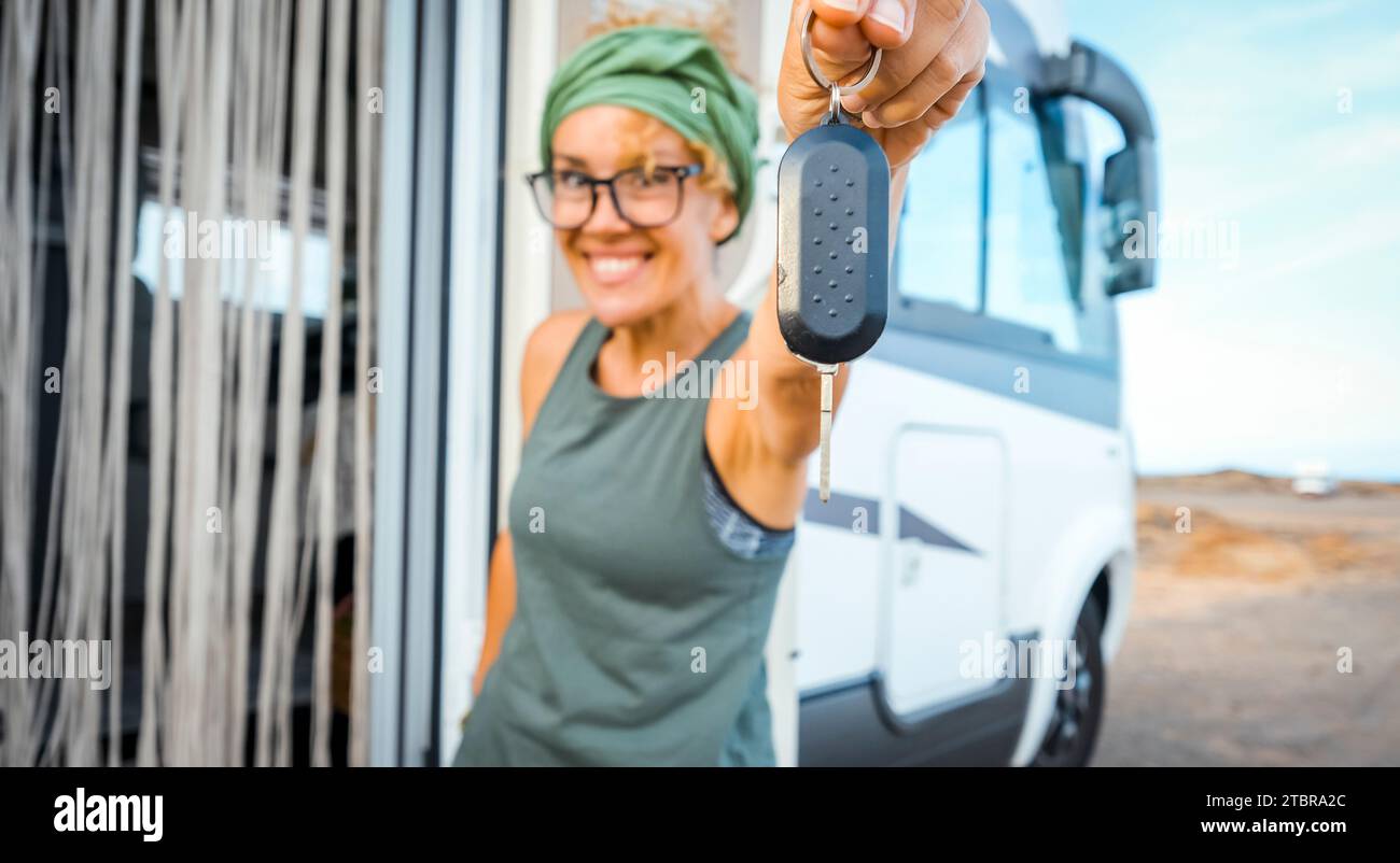Happy new buyer owner of camper van motorhome show at the camera her keys with happiness. New house and vehicle for vacation concept scene. Travel vanlife lifestyle. Adventure. Nomadic people female Stock Photo