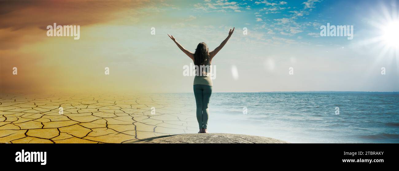 A woman stands with outstretched arms on a rock as a silhouette Stock Photo