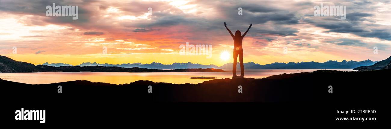 The Lofoten archipelago at sunset, silhouette of a woman with outstretched arms Stock Photo