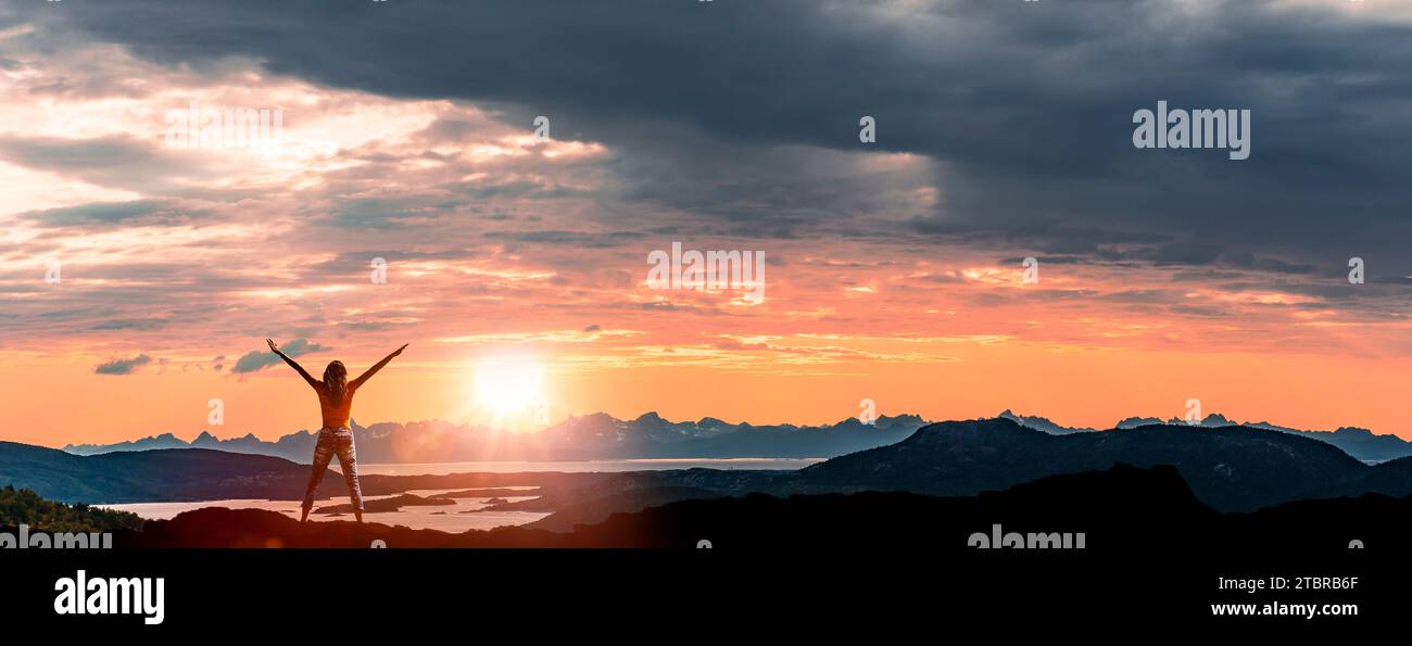 The Lofoten archipelago at sunset, silhouette of a woman with outstretched arms Stock Photo