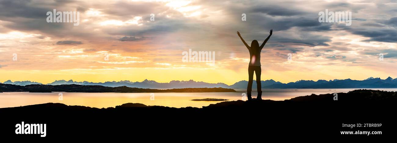 The Lofoten archipelago at sunset, silhouette of a woman with outstretched arms Stock Photo