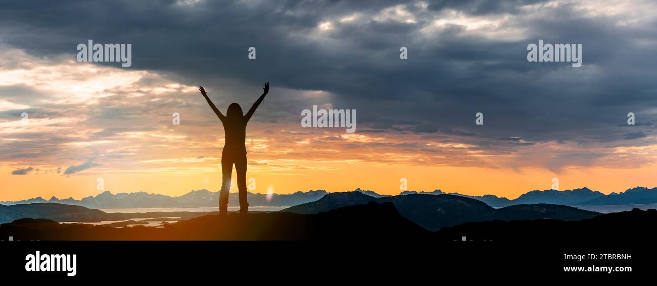 The Lofoten archipelago at sunset, silhouette of a woman with outstretched arms Stock Photo