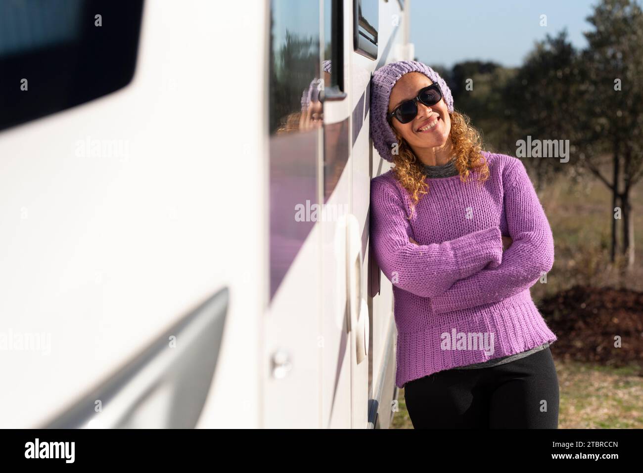 One happy woman traveler standing and posing smiling at the camera against her white modern camper van motorhome tiny house. Alternative concept of travel and freedom. Female people adventure alone Stock Photo