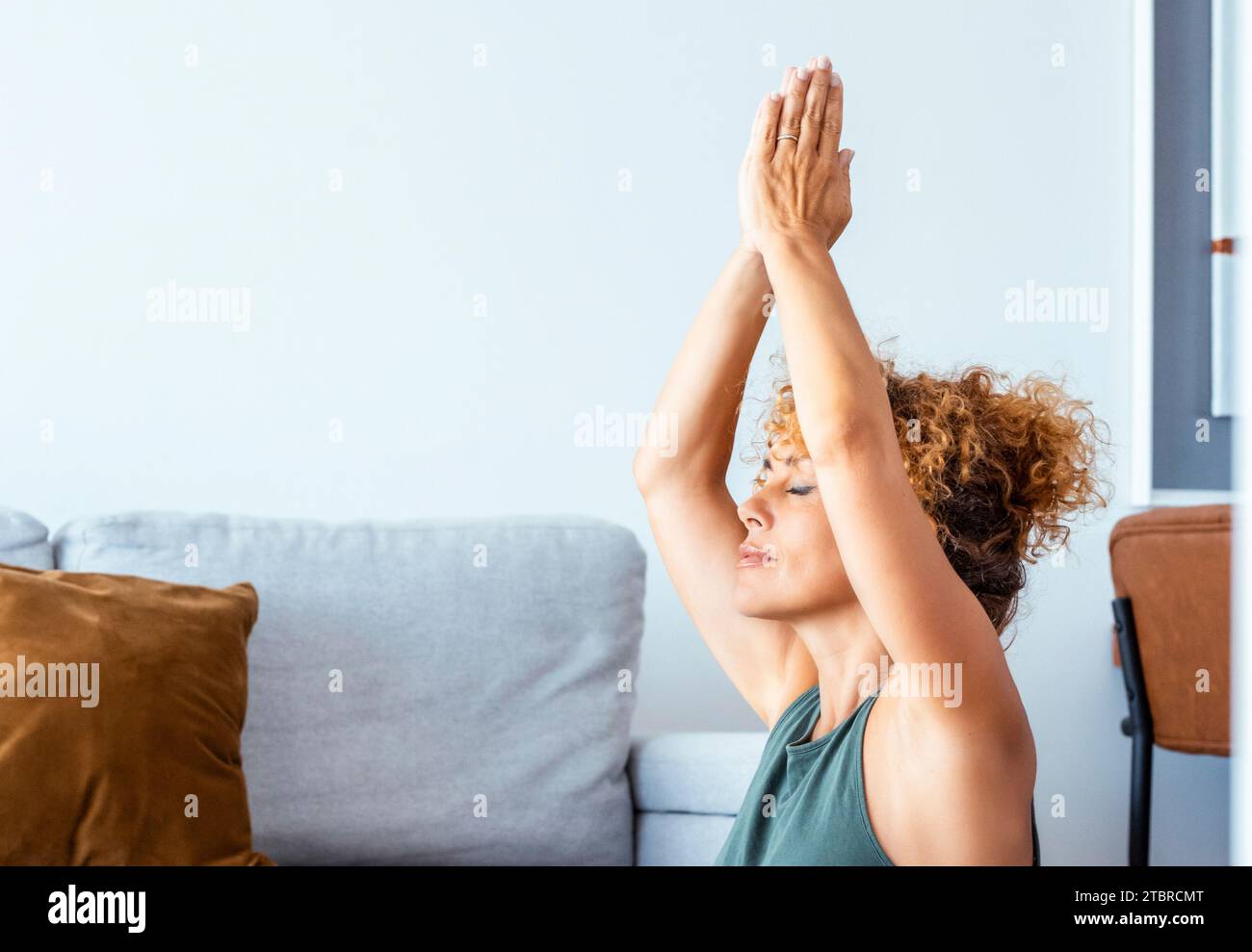 One young adult woman doing yoga exercises at home alone in living room. Healthy workout pilates lifestyle people in indoor sport activity. Wellbeing and interior mental balance mindful female mature Stock Photo