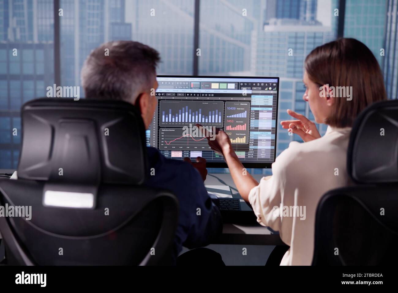 Working Analyst at Desktop PC with Spreadsheets Stock Photo