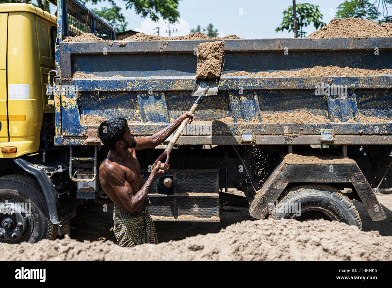 Workers shovelling sand into trucks in Jaflong, Bangladesh. Stock Photo