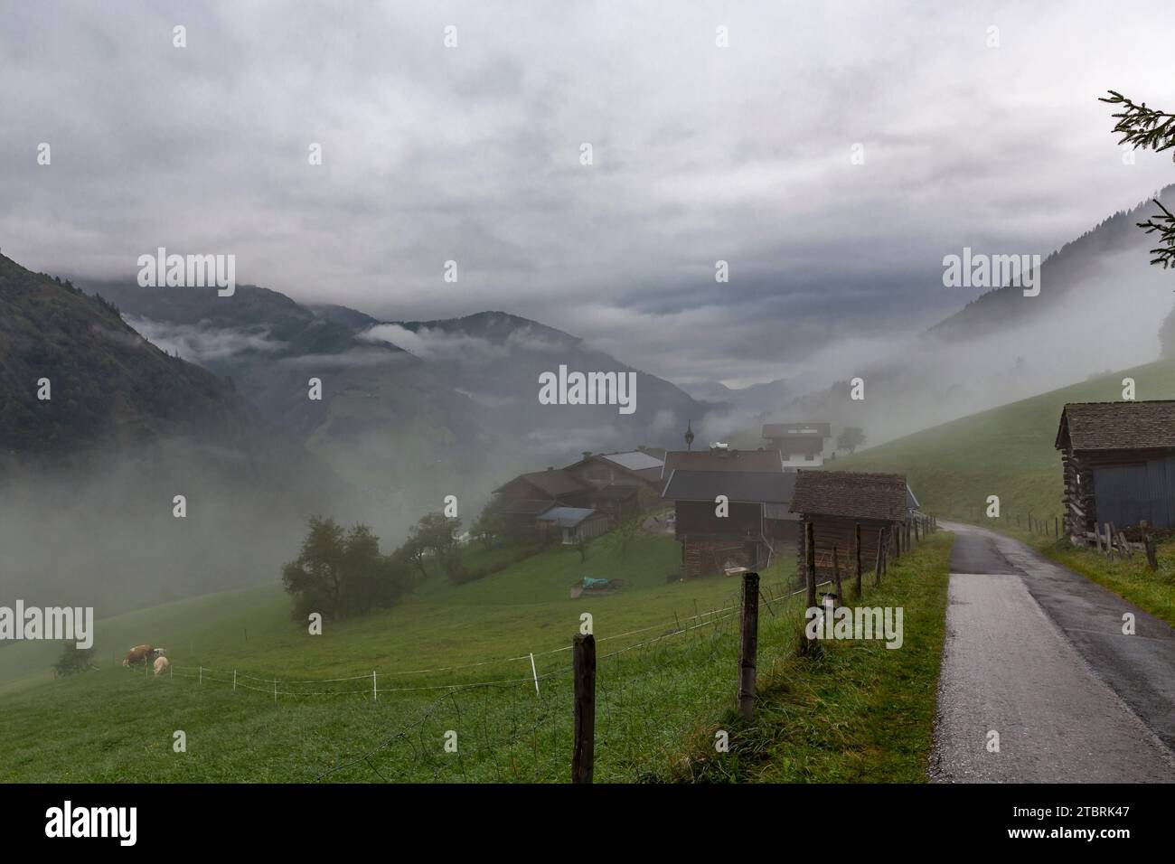 Farmhouses in the morning fog and storm clouds, Fröstlberg in the Rauris Valley, Rauris, Pinzgau, Salzburger Land, Austria Stock Photo