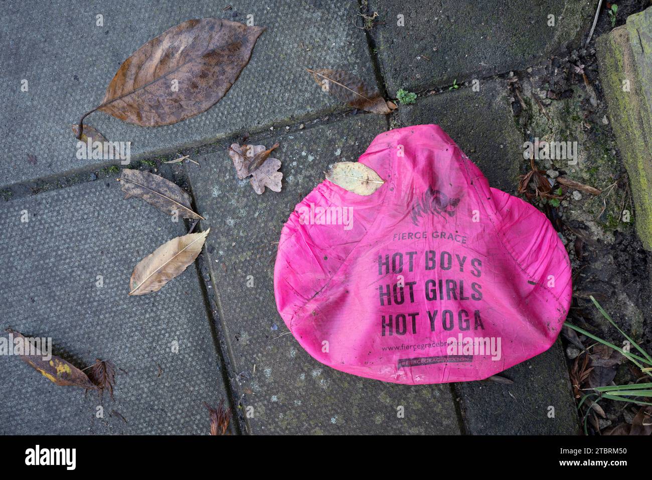 detail of a discarded pink bike seat cover that advertises a Brixton yoga business and other adult lifestyle interests lies forgotten on the pavement of a south London residential pavement. on 8th December 2023, in London, England. Stock Photo