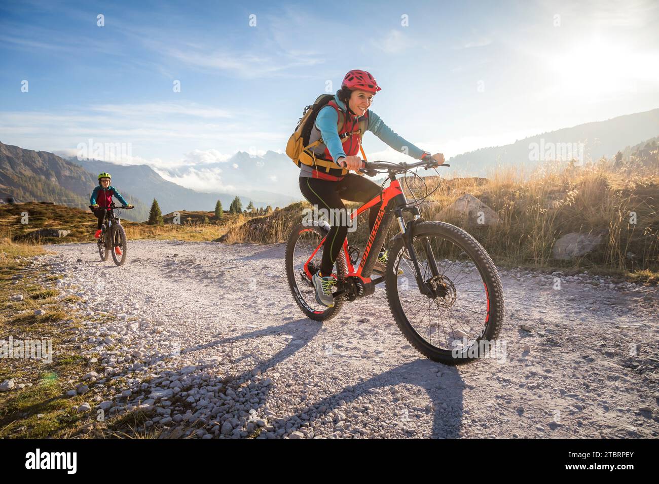 Italy, Veneto, province of Belluno, outdoor family activities, mother and teenage daughter along a dirt road riding their respective e-bikes Stock Photo