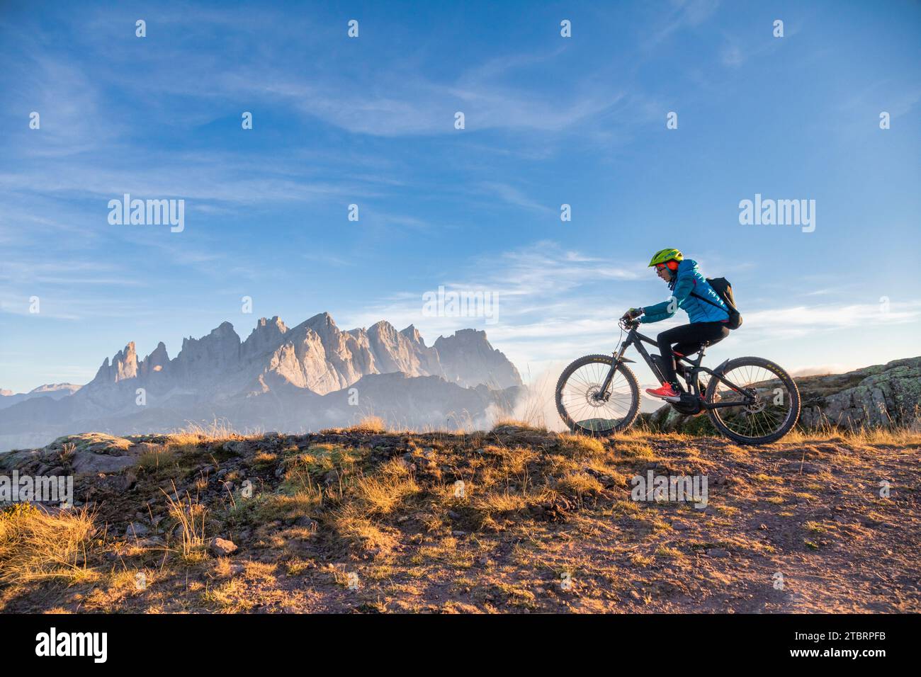 Italy, Veneto, province of Belluno, Falcade, outdoor activities with family, young cyclist riding an e-bike in the mountains, in the background the Pale di San Martino chain at sunset Stock Photo