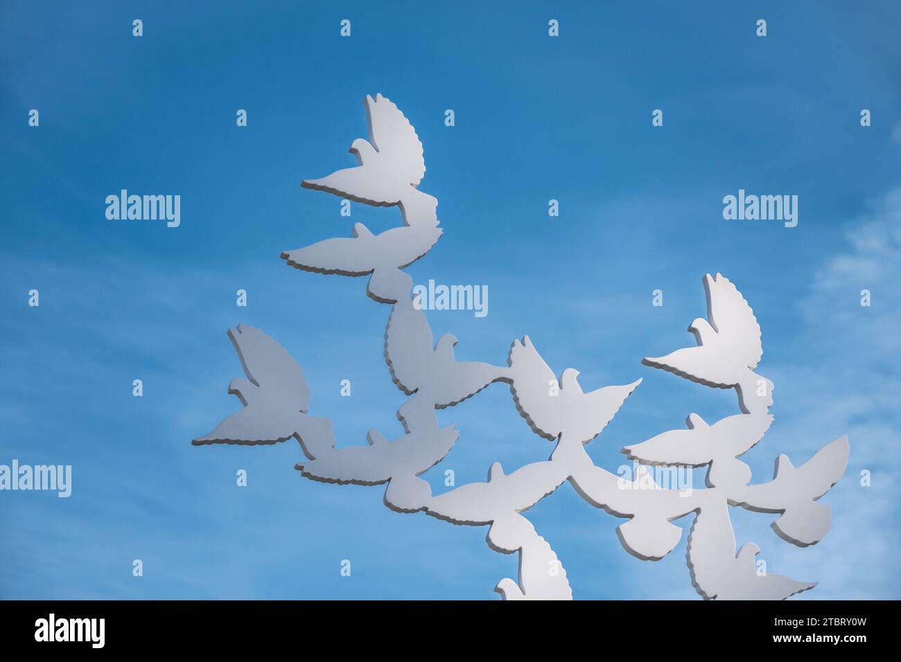 Statue of white pigeons flying on the blue sky background. Peace