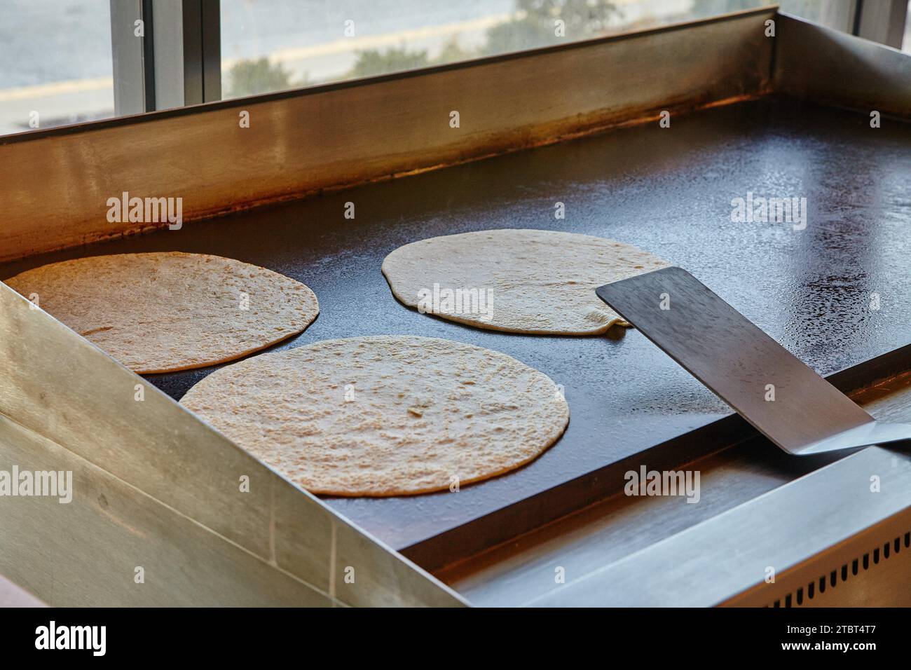 Restaurant Setting Cooking Tortillas on Griddle in Ambient Light Stock