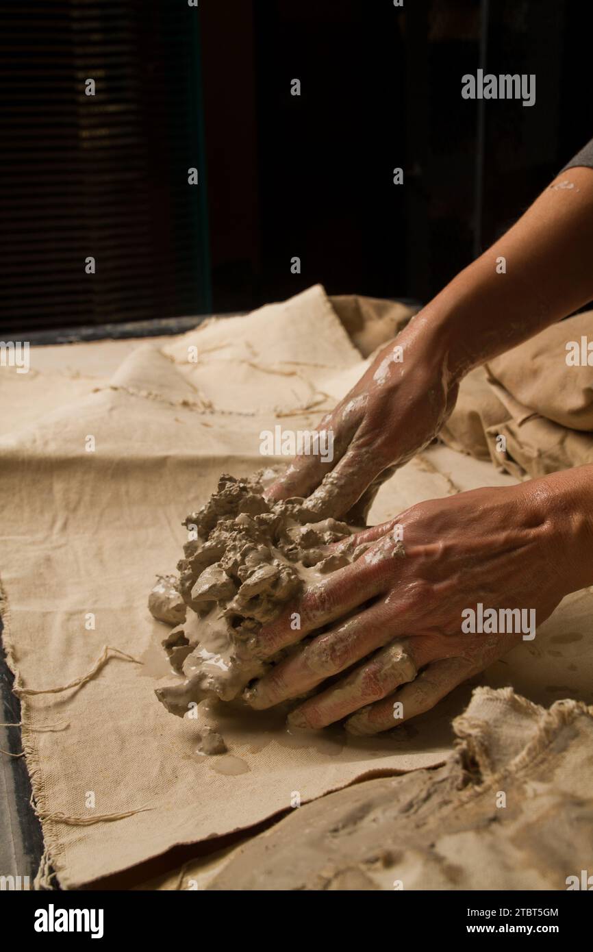 Artisan Hands Kneading Clay in Warmly Lit Pottery Studio Stock Photo