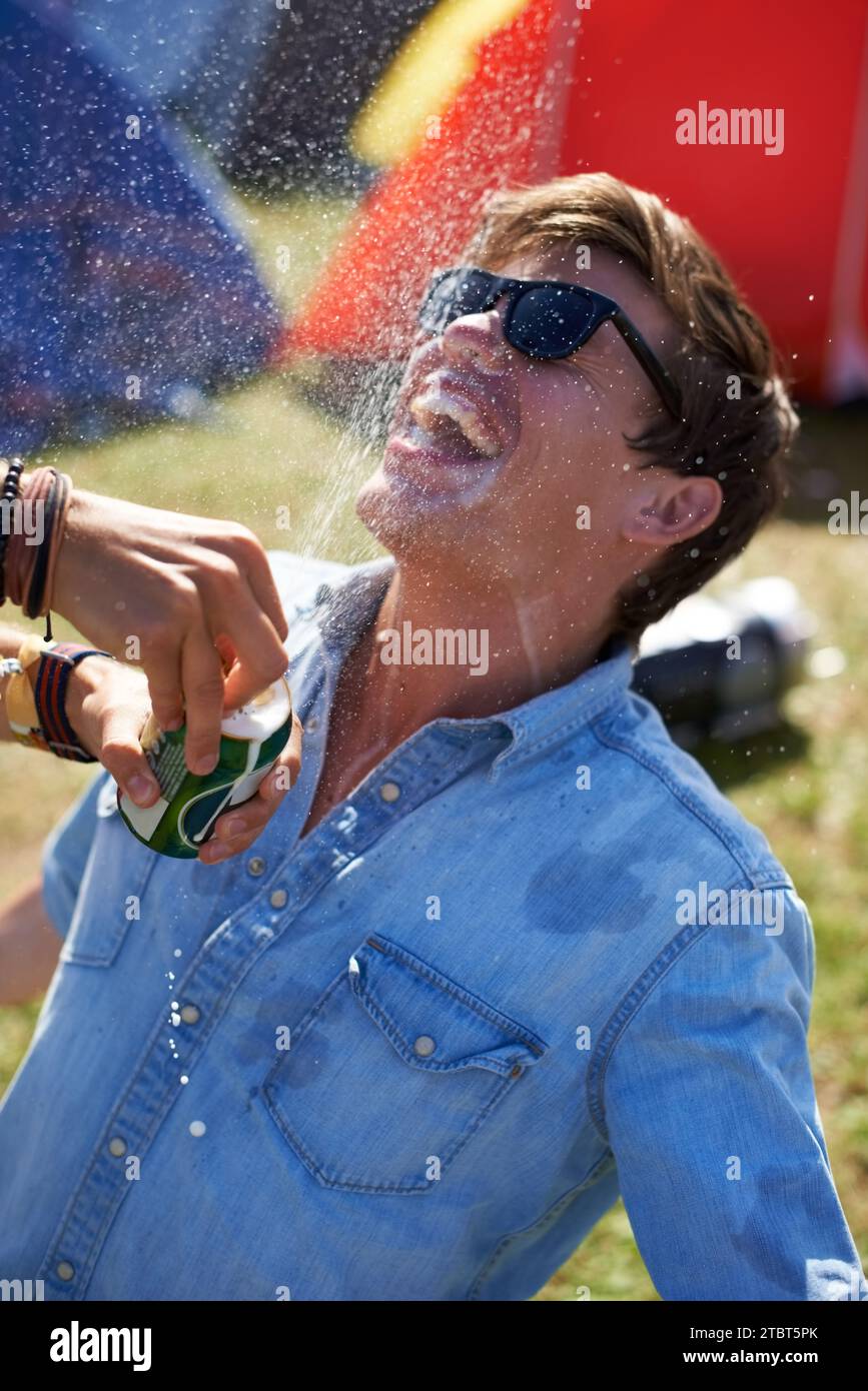 Music festival, alcohol and man with beer outdoors splash for drunk party, celebration and camp event. Happy, excited and person with beverage spray Stock Photo