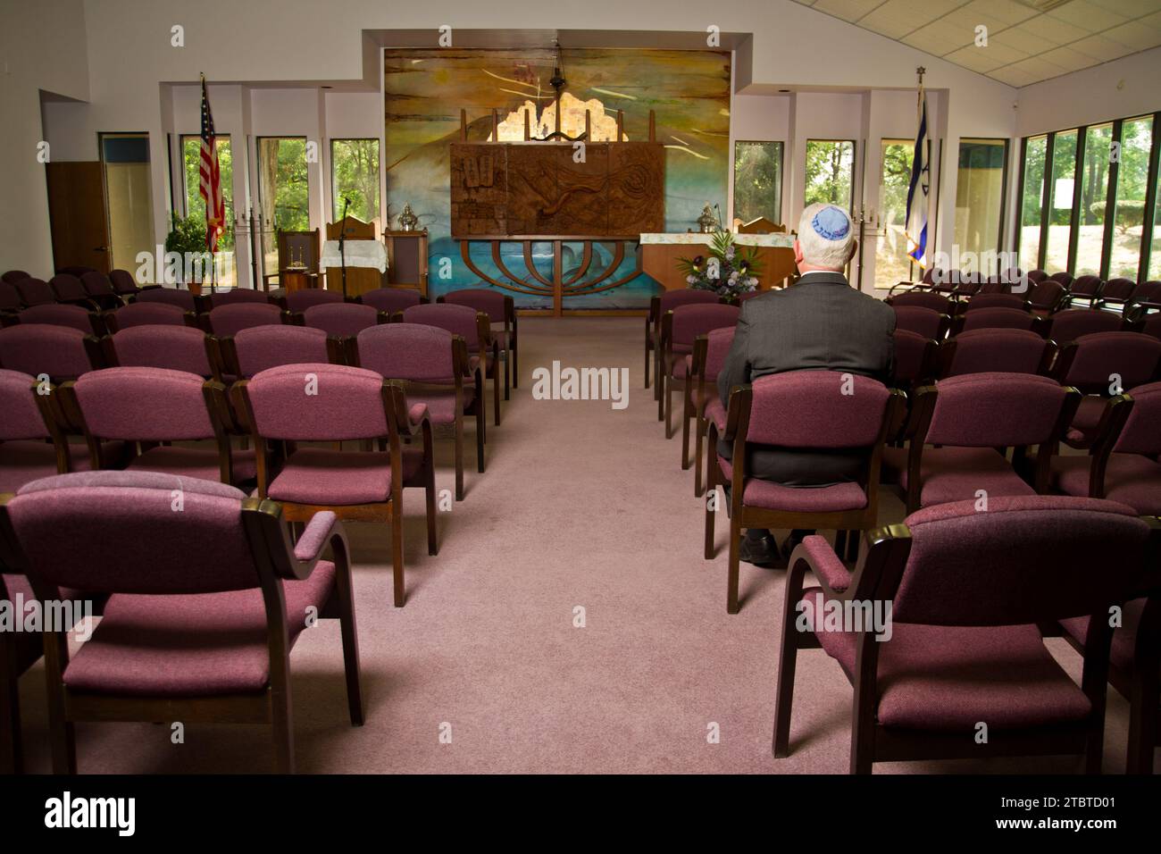 Solitary Worship in Well-lit American Synagogue Interior Stock Photo
