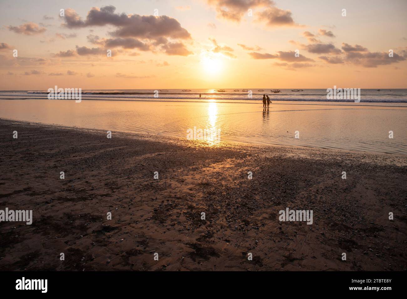 Dreamlike sunset on the dream beach of Kuta, small waves in the sea and the reflection of the sky in the shallow water, tropical Bali, Indonesia Stock Photo
