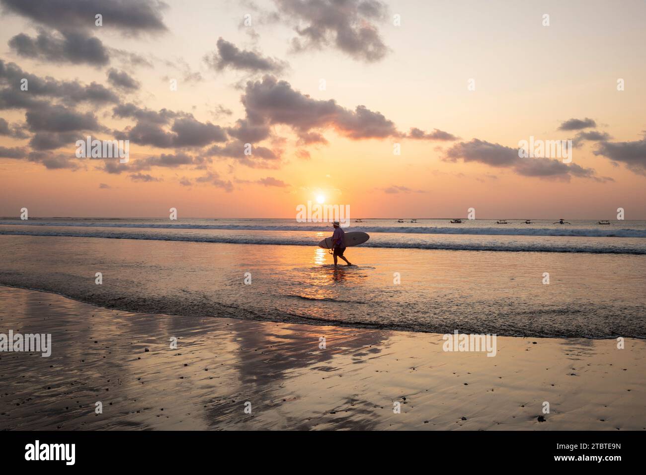 Dreamlike sunset on the dream beach of Kuta, small waves in the sea and the reflection of the sky in the shallow water, tropical Bali, Indonesia Stock Photo