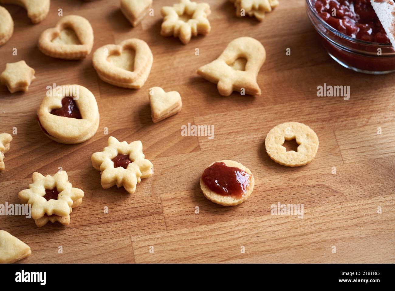 Filling circle shaped Linzer Christmas cookie with red strawberry marmalade Stock Photo