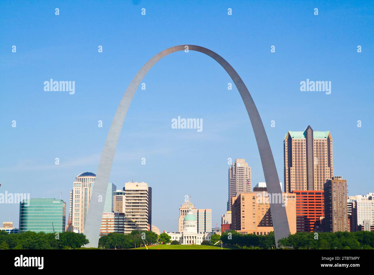 Gleaming Gateway Arch Under Blue Sky Amidst St. Louis Cityscape Stock Photo