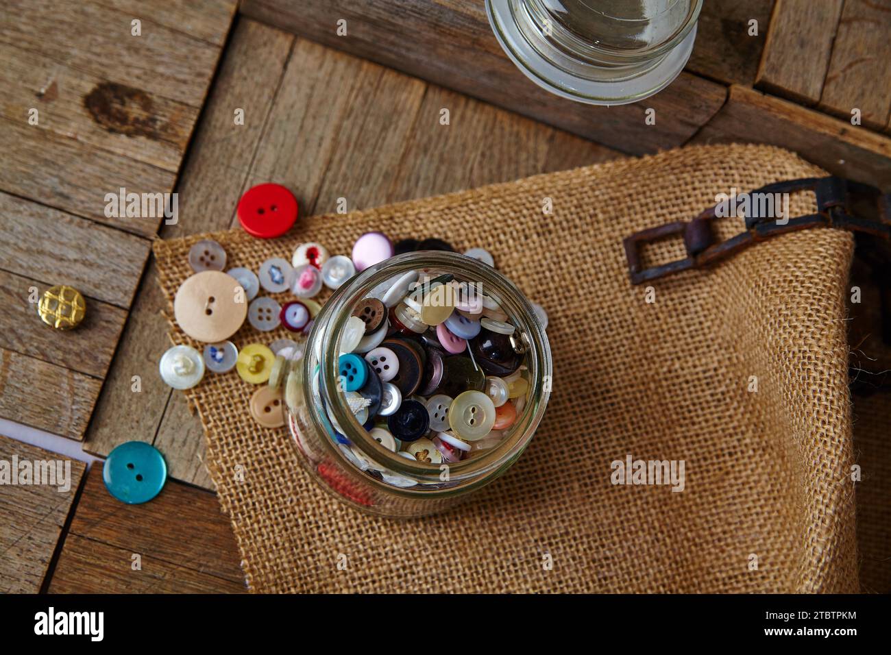 Overhead View of Colorful Buttons in Glass Jar on Rustic Wooden Table Stock Photo