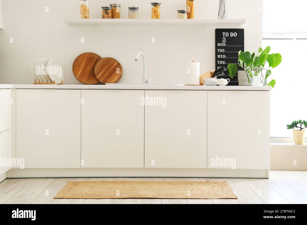 Interior of light kitchen with counters and wicker carpet Stock Photo ...