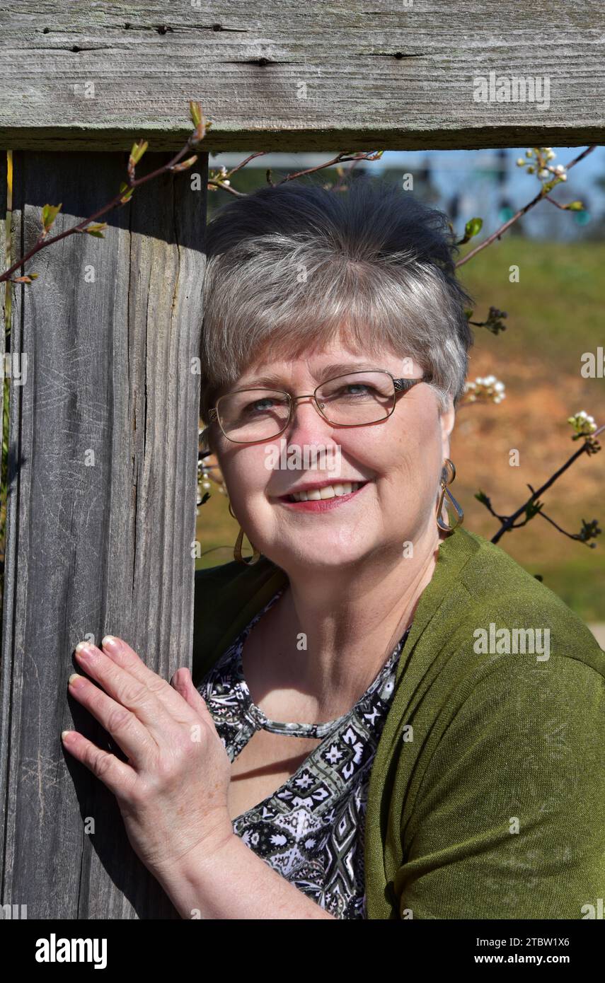 Next door neighbor peeks through the hole in the fence. She is wearing