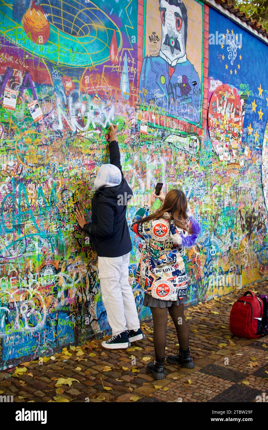 A colourful young couple add their own personal touch to the John Lennon wall, Prague, Czech Republic Stock Photo