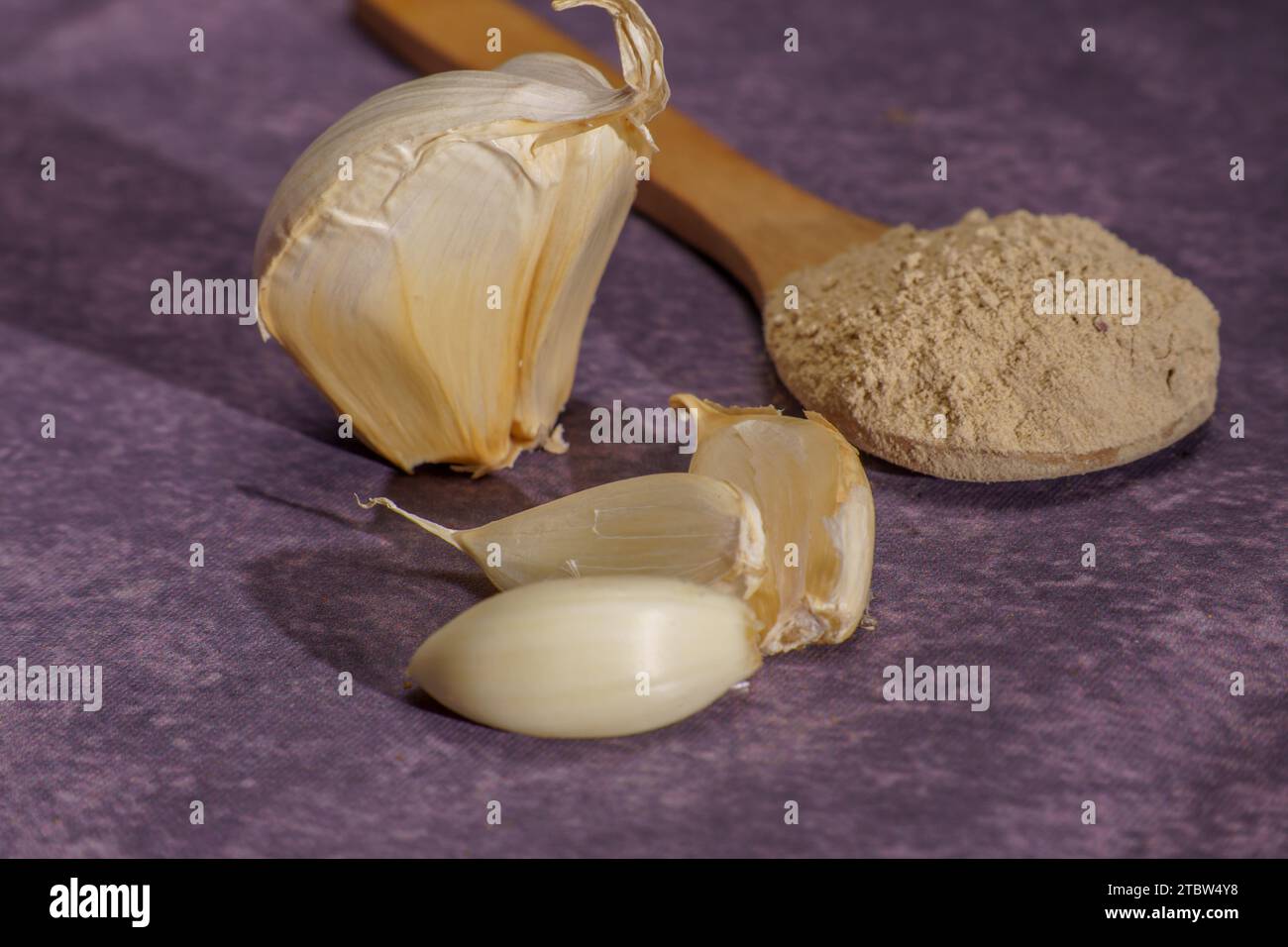 whole garlic cloves and crushed garlic in a wooden spoon Stock Photo