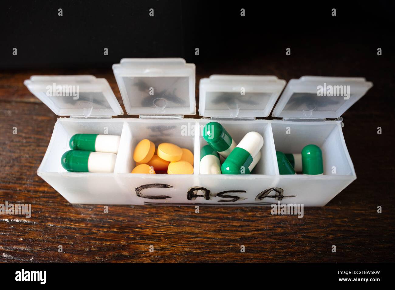 pill organizer box, with orange pills and other green ones Stock Photo