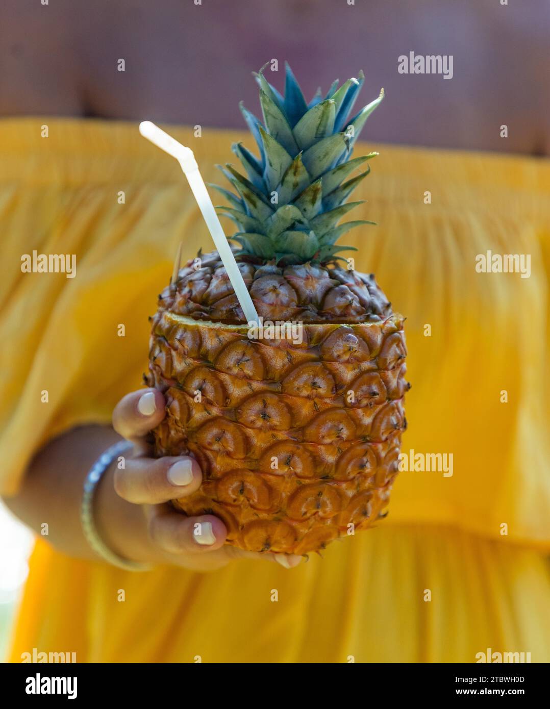 A picture of someone holding a pineapple juice in the hand Stock Photo