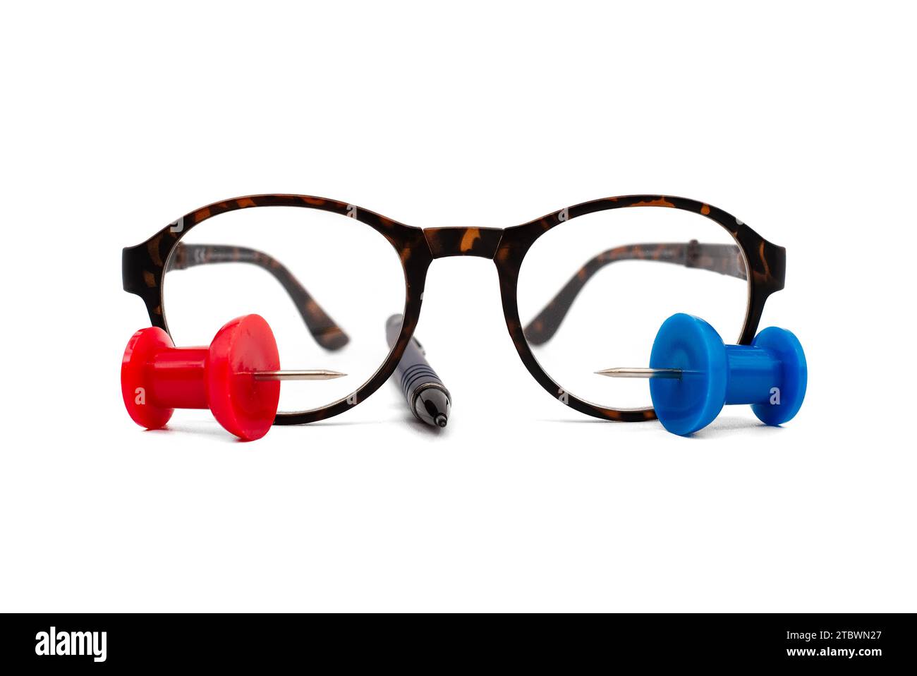 Reading glasses with tortoiseshell frames, pen and colorful red and blue thumb tack over a white background with copy space in a business still life Stock Photo