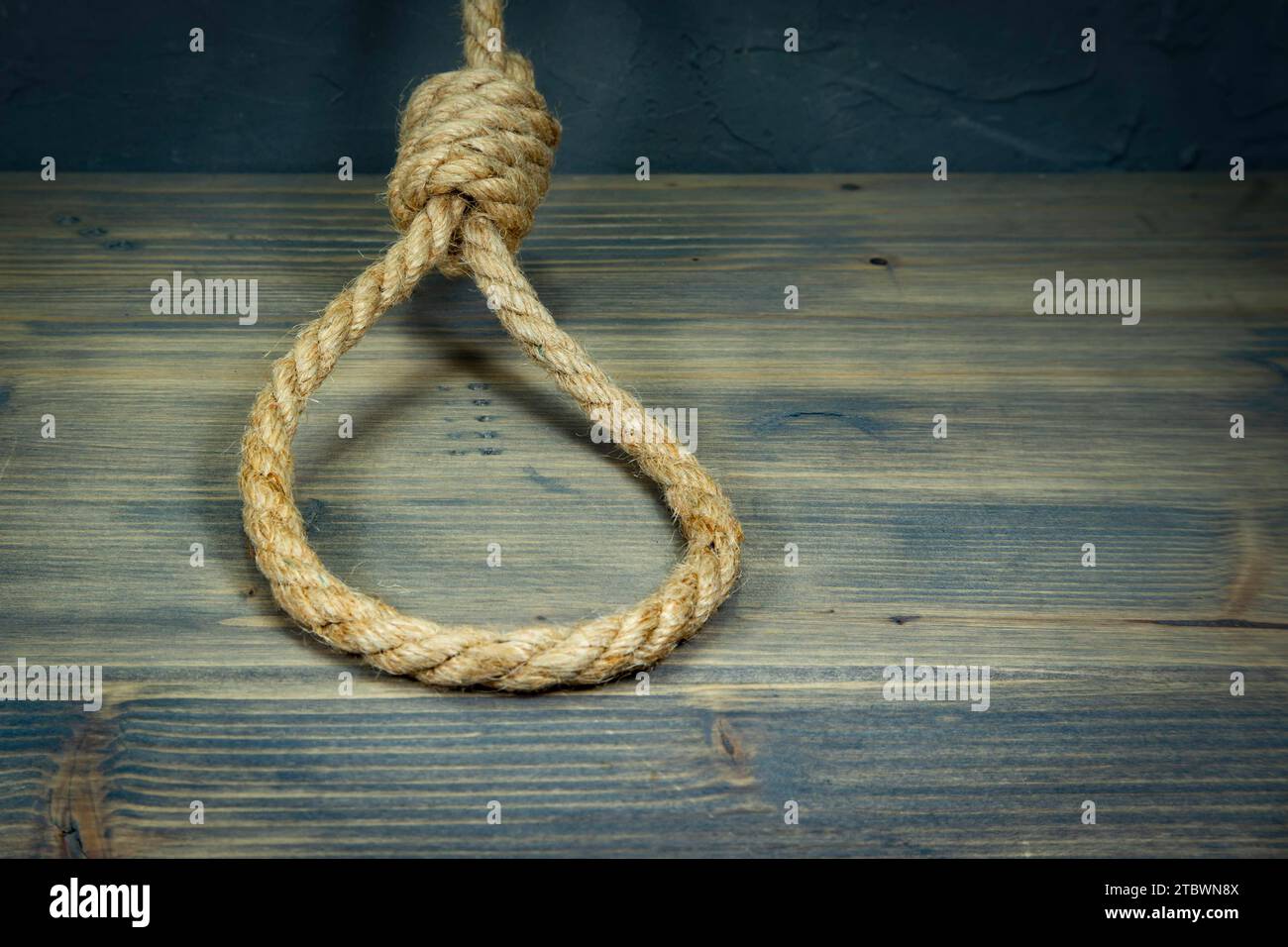 Hangman's knot on a rustic wooden table in a conceptual image of death penalty or suicide Stock Photo