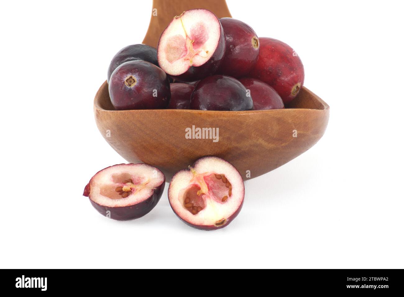 Half cut cranberry berry and fresh cranberries in wooden spoon isolated on white background, full depth of field Stock Photo