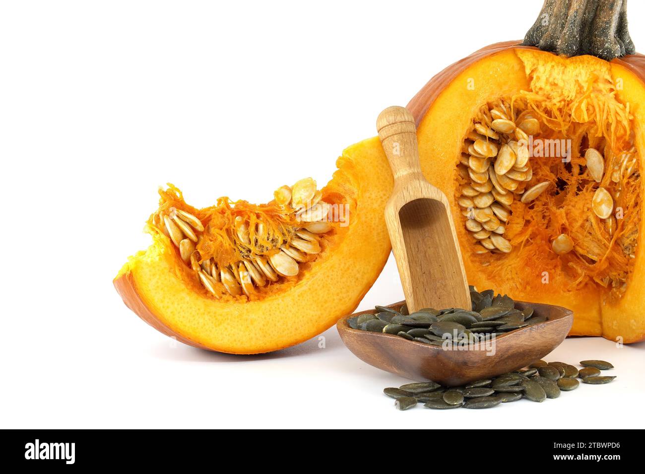 Dried hulled pumpkin seeds or pepitas in wooden scoop and fresh pumpkin